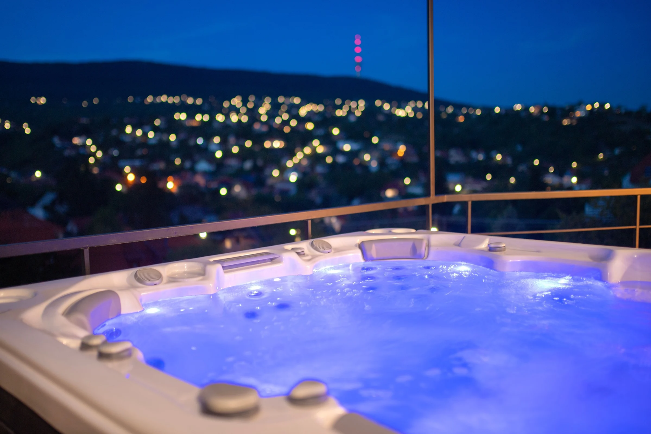 Kivilágított jacuzzi a teraszon sötétedéskor.