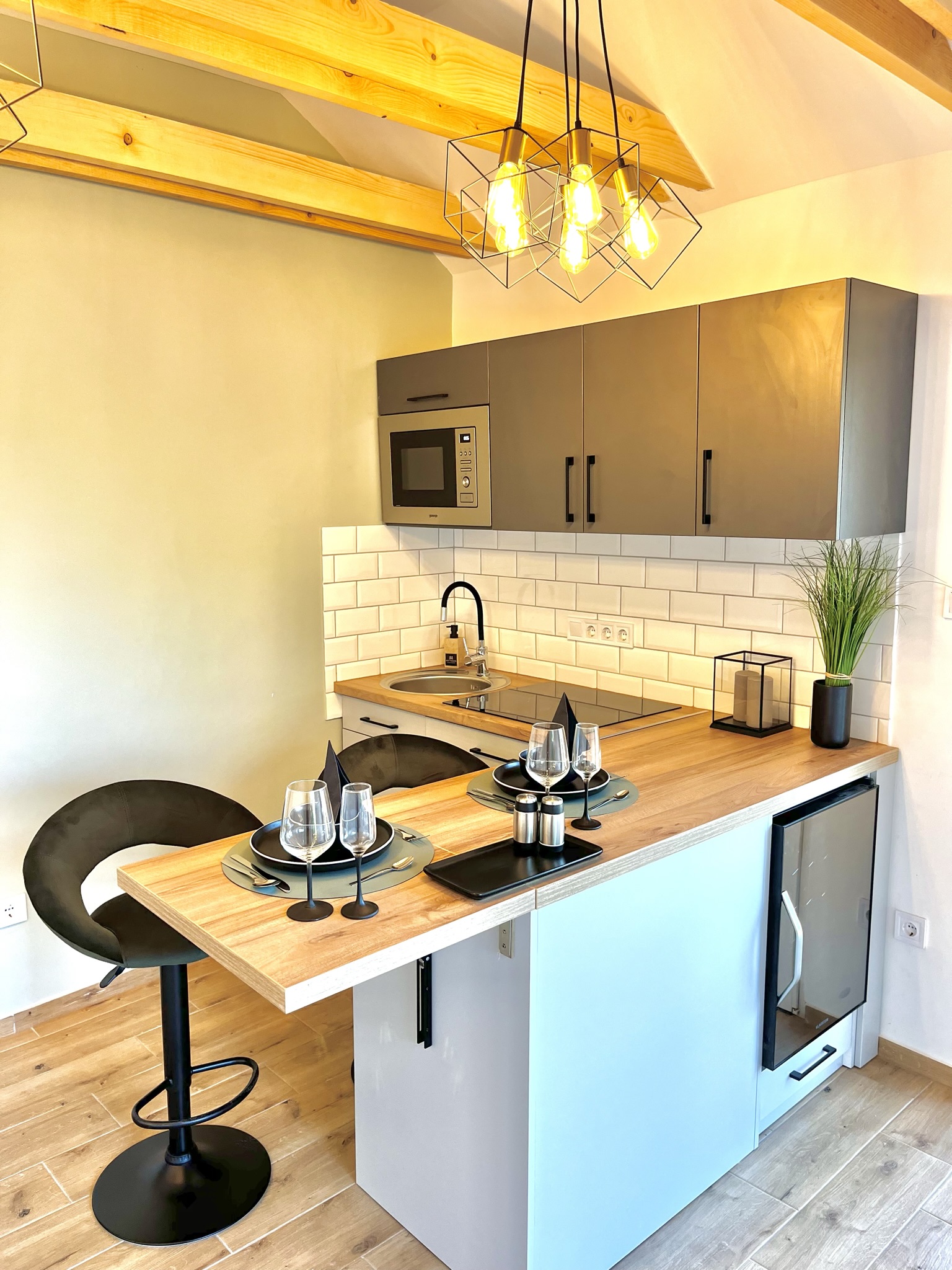 Szépen bevilágított full felszereltségű konyha és egy megterített asztal.